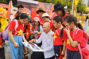 Nhiếp ảnh gia Nguyễn Á trò chuyện cùng các em học sinh tham quan triển lãm. Ảnh: L.N.