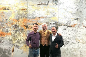 Họa sĩ Ngô Thanh Hùng (bìa phải) chụp ảnh cùng khách tham quan triển lãm.