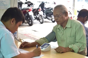 Cán bộ y tế kiểm tra huyết áp và tư vấn phác đồ điều trị phù hợp cho người có công với cách mạng. Ảnh: H.P