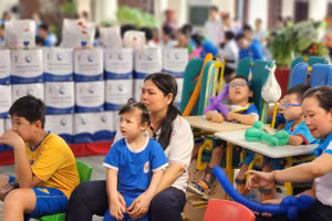 Các em nhỏ cùng các cô chăm chú xem chương trình Trung thu tại trung tâm. Ảnh: H.P