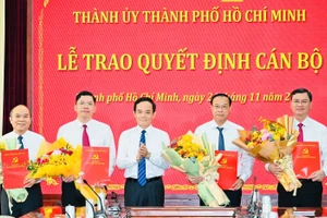 Ông Trần Lưu Quang, Bí thư Thành ủy TPHCM (giữa) trao quyết định và tặng hoa chúc mừng các tân lãnh đạo HĐND và UBND TPHCM. Ảnh: SGGP