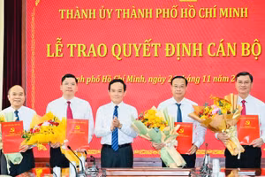 Ông Trần Lưu Quang, Bí thư Thành ủy TPHCM (giữa) trao quyết định và tặng hoa chúc mừng các tân lãnh đạo HĐND và UBND TPHCM. Ảnh: SGGP