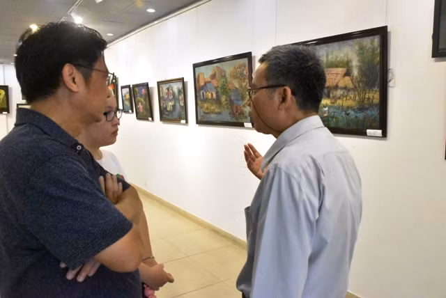 Họa sĩ Vũ Xuân Hương (bìa phải) trao đổi cùng một số phụ huynh và HS tại triển lãm