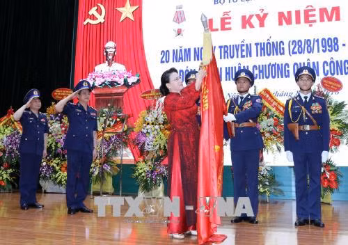 Chủ tịch Quốc hội Nguyễn Thị Kim Ngân gắn Huân chương Quân công hạng Ba lên lá cờ truyền thống của lực lượng CSB Việt Nam. Ảnh: TTXVN