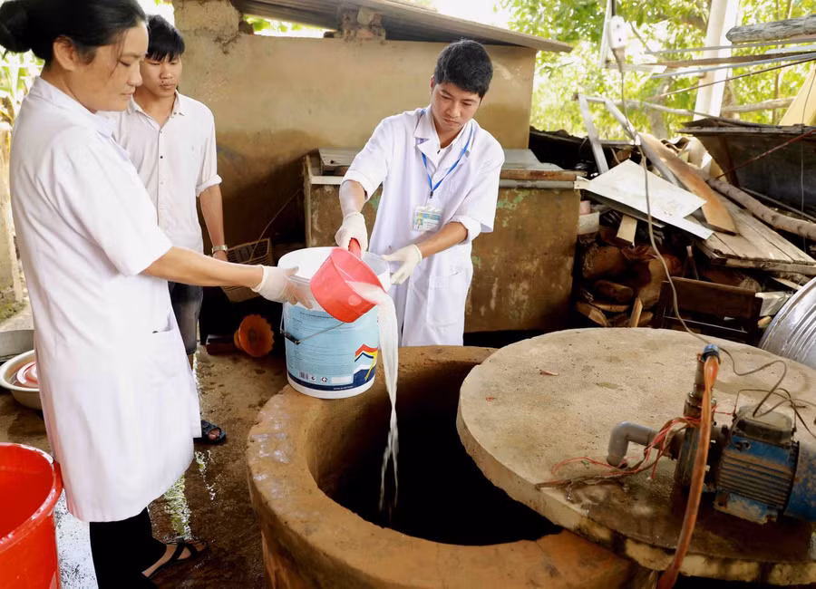 Nhân viên Trung tâm Y tế dự phòng huyện Lệ Thủy tiến hành khử khuẩn nước sinh hoạt bằng dung dịch Cloramin B cho hộ Lê Thị Đào ở thôn Mai Thúy, xã Mai Thủy. Ảnh: Vũ Sinh – TTXVN.