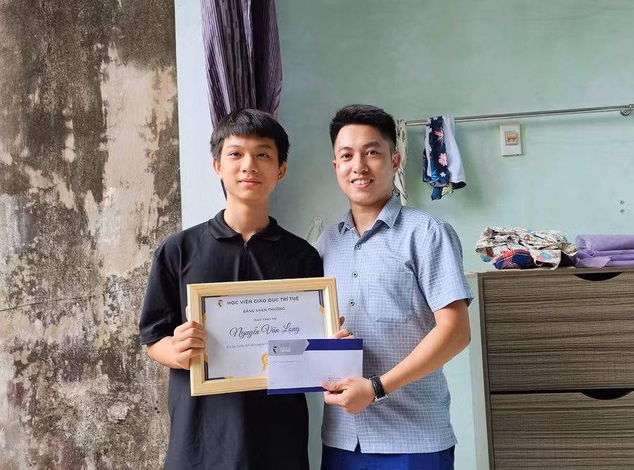 Á khoa Nguyễn Văn Long (bên trái) nhận phần thưởng của Học viện Giáo dục Trí tuệ.