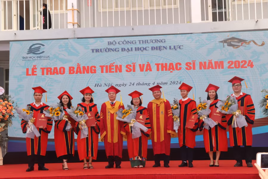 PGS.TS Vũ Đình Ngọ - Chủ tịch Hội đồng trường (bên trái) và PGS.TS Đinh Văn Châu - Hiệu trưởng trường Đại học Điện lực trao bằng, chúc mừng các tân Tiến sĩ.