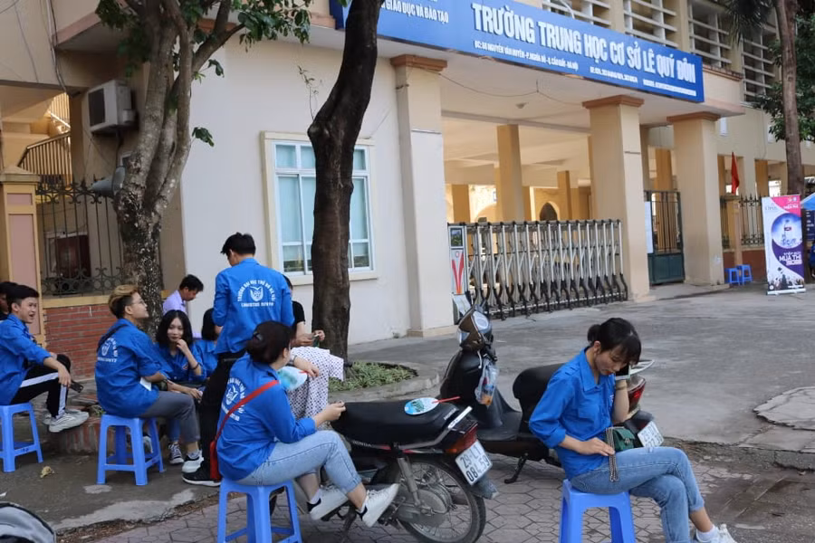 Các sinh viên tình nguyện tranh thủ nghỉ ngơi, chờ sĩ tử thi tại điểm trường THCS Lê Quý Đôn, quận Cầu Giấy (Hà Nội).