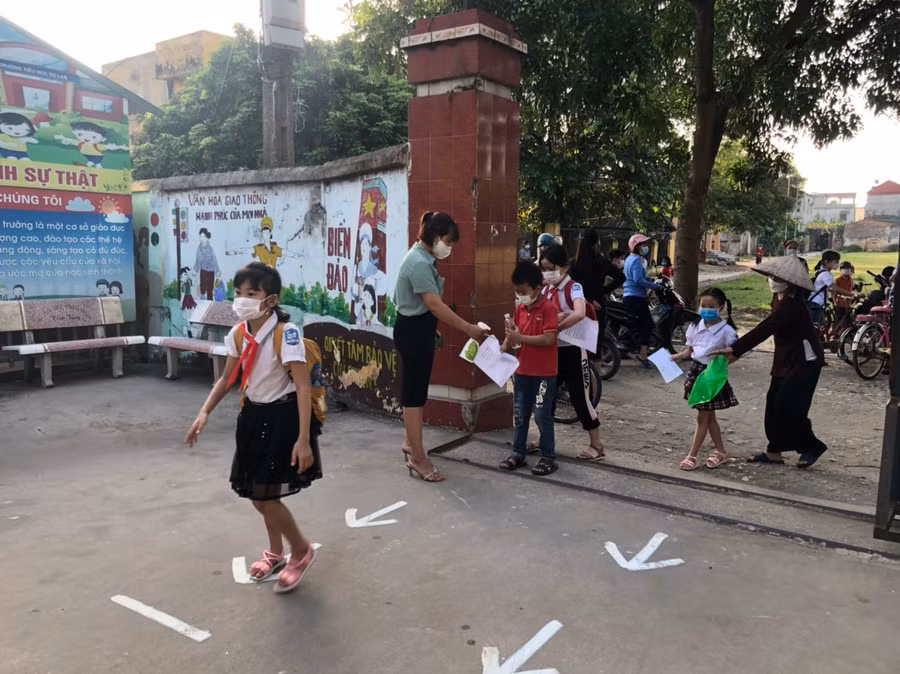 Học sinh đi theo chỉ dẫn của giáo viên để đảm bảo an toàn phòng dịch.