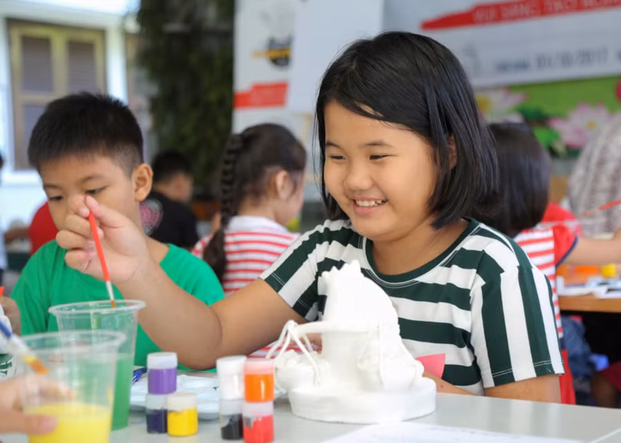Nụ cười trong trẻo của cô bạn nhỏ trước khi tô màu cho bức tượng Humpty Dumpty