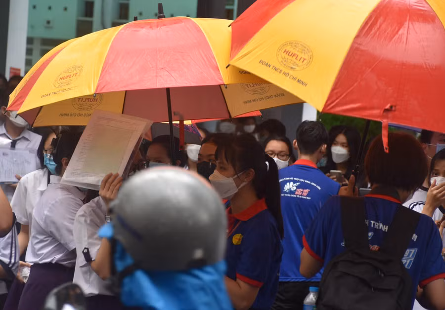 Các tình nguyện viên che dù cho thí sinh rời khởi điểm thi đến xe phụ huynh.