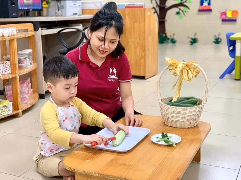 Cô giáo Trường Mầm non Tân Mai đang hướng dẫn học sinh gọt rau quả. Ảnh NTCC.