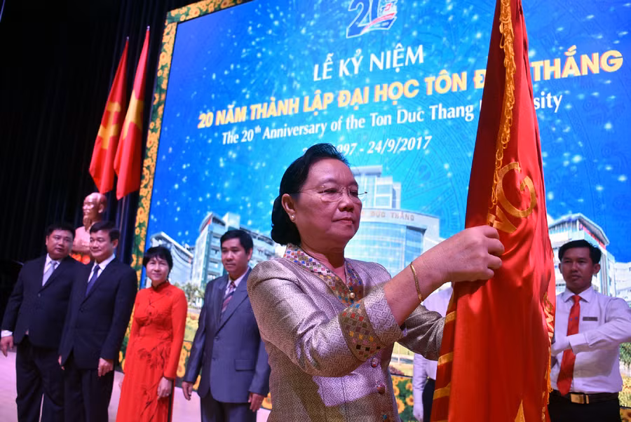 Bà Sengdeuane Lachanthaboun - Bộ trưởng Bộ Giáo dục và Thể thao Lào - gắn Huân chương Hữu nghị lên cờ truyền thống TDTU