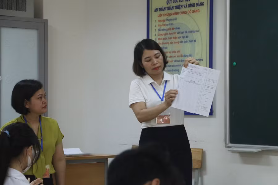 Giám thị phát giấy làm bài thi cho các thí sinh.