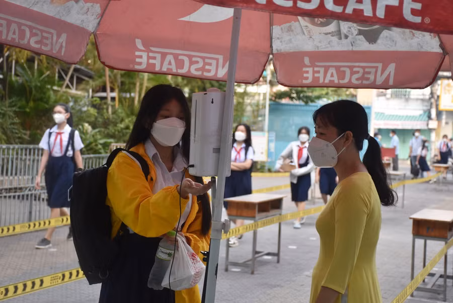 Học sinh Trường THCS Chánh Hưng (Q.8, TPHCM) sử dụng máy đo thân nhiệt, nước rửa tay sát khuẩn tự động trước khi vào lớp.