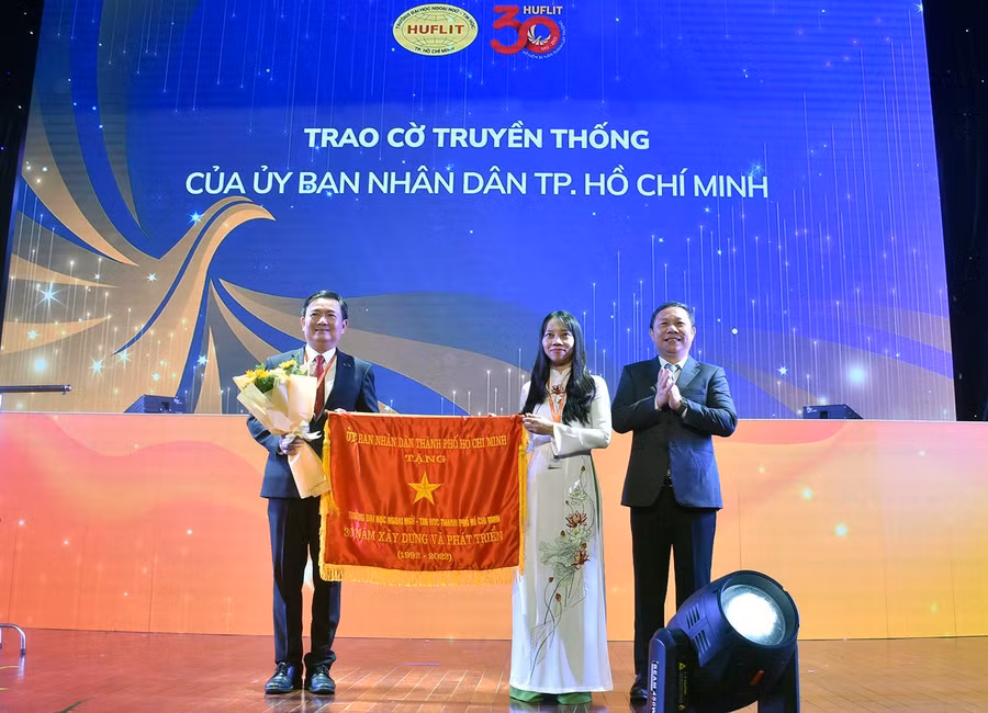Phó Chủ tịch UBND TPHCM Dương Anh Đức trao cờ truyền thống của UBND TPHCM cho đại diện lãnh đạo HUFLIT.
