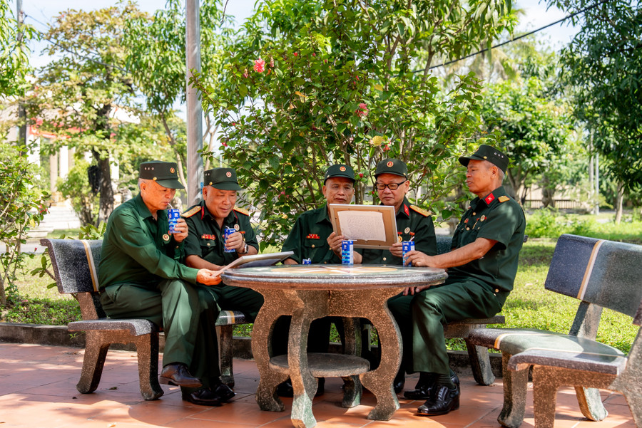Các bác cựu chiến binh chăm chú đọc những dòng chữ nhỏ, được các em gửi kèm trong mỗi bức tranh (Ảnh: Duy Cường). anh-4a-vnm.jpg