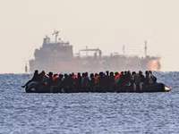 Xuồng nhỏ chở người di cư hướng về Dover, phía sau là một tàu chở hàng rời, gần Calais, Pháp, ngày 6/9/2026.