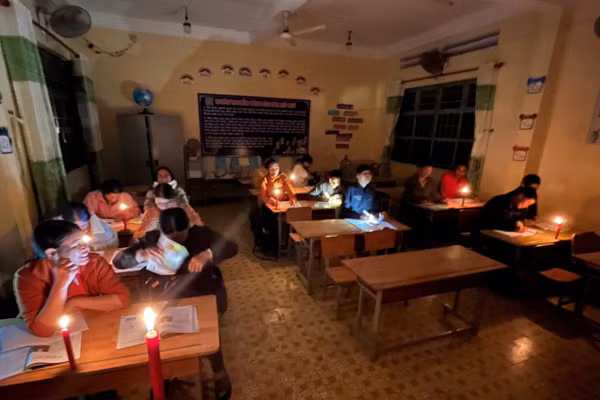 Các học viên của lớp xóa mù chữ học dưới ánh nến.