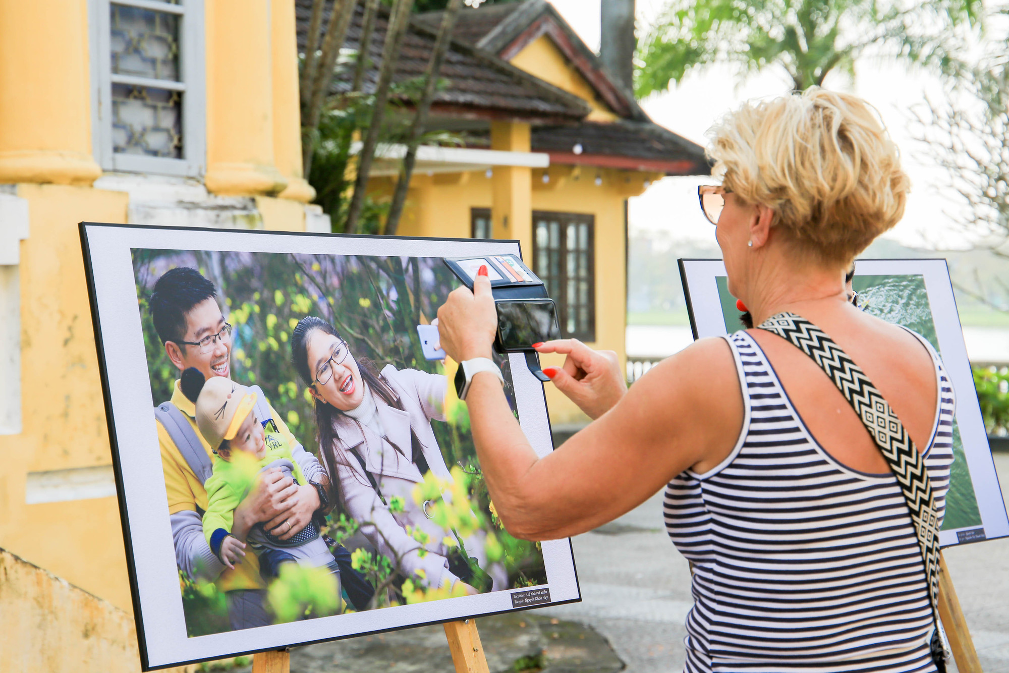 Một du khách nước ngoài thích thú với tác phẩm nghệ thuật về chủ đề gia đình tại triển lãm.