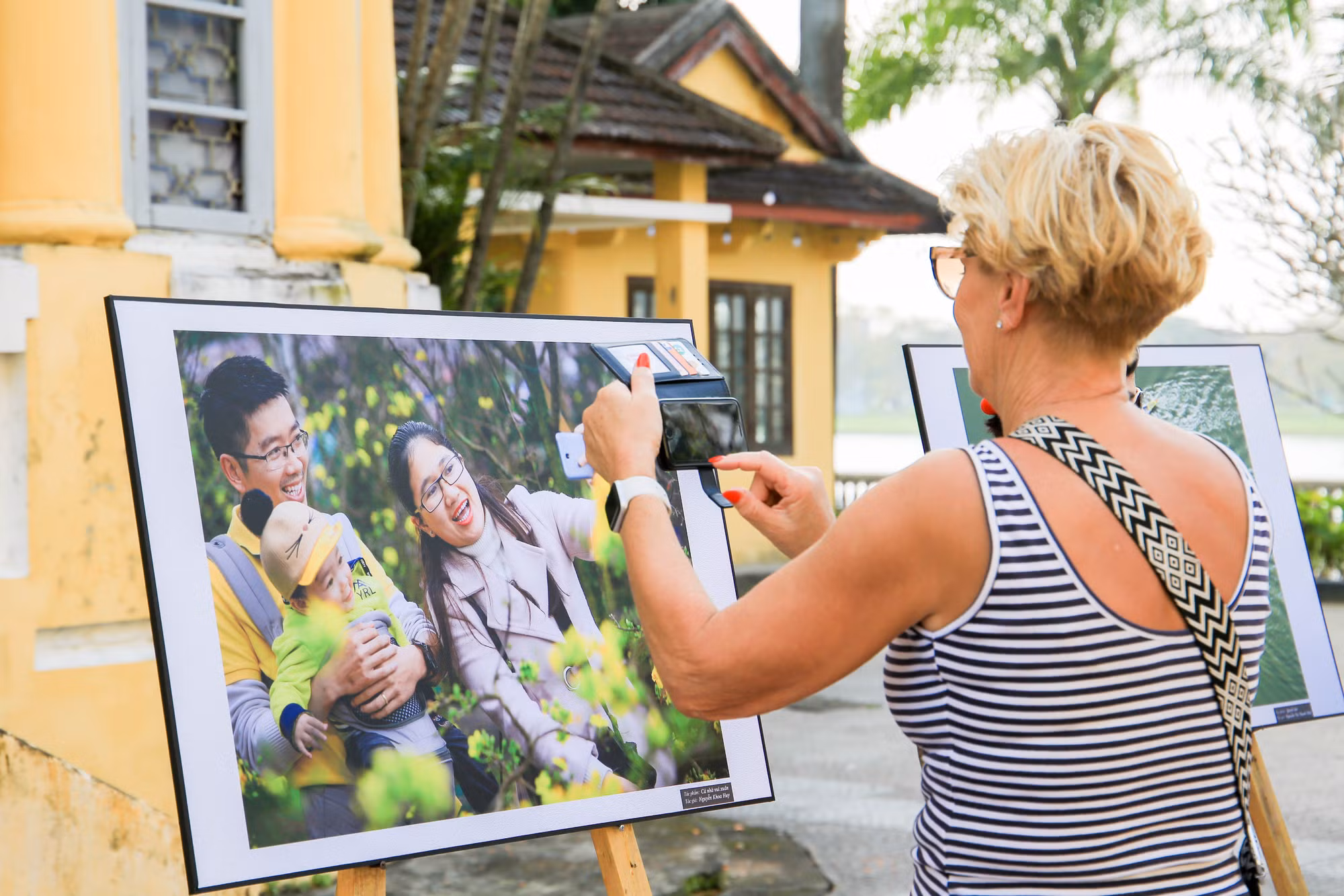 Một du khách nước ngoài thích thú với tác phẩm nghệ thuật về chủ đề gia đình tại triển lãm.
