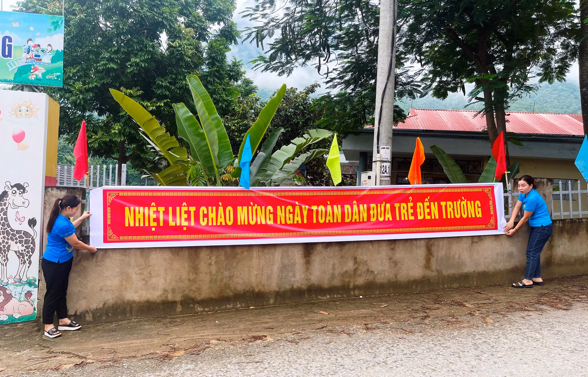 Cô giáo Trường Mầm non Tam Chung (Mường Lát) treo băng rôn, chuẩn bị cho Ngày hội toàn dân đưa trẻ đến trường. Ảnh: TL.