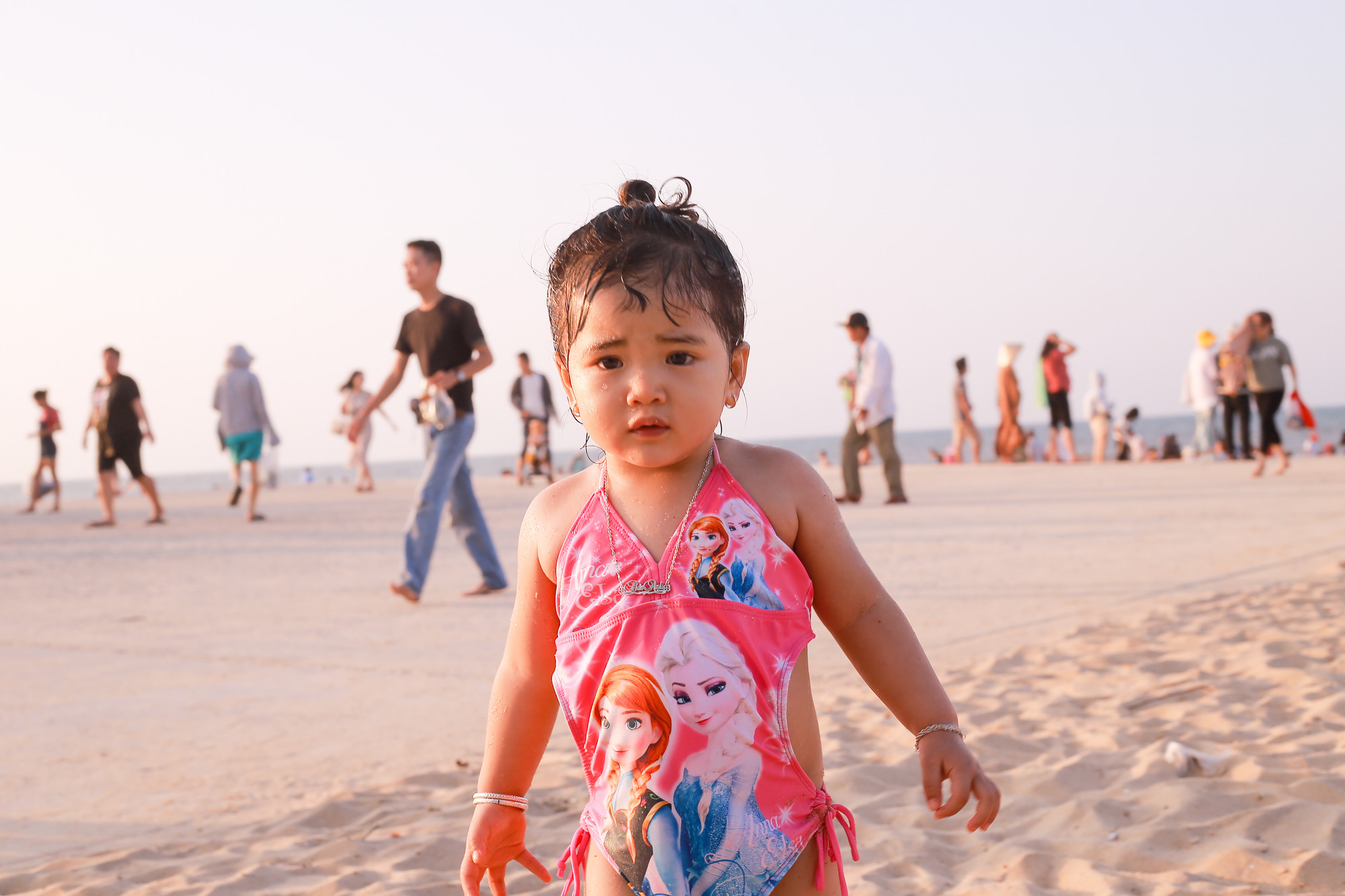 Một em bé cùng gia đình tắm biển và vui chơi tại bãi cát.