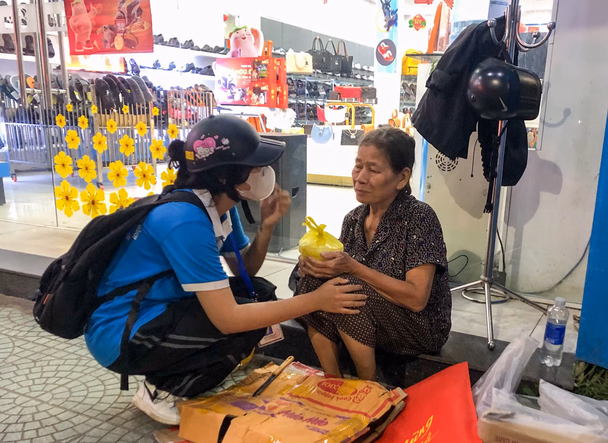 Ân cần hỏi thăm và gửi phần cháo cho một cụ bà vô gia cư trước Nhà sách Phú Xuân tại đường Trần Hưng Đạo, TP Huế.