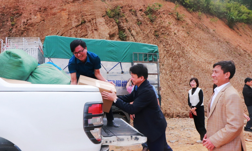 Bí thư Huyện ủy Mường Lát (áo đen) cùng xúm tay bốc xếp hàng sang tải. Ảnh: Đăng Chung