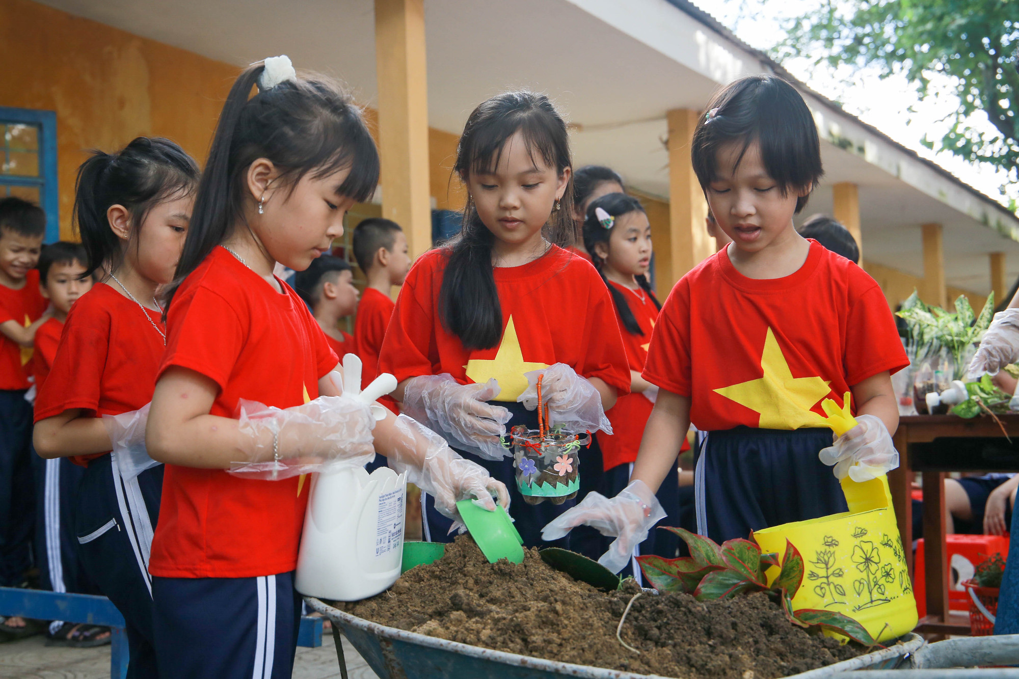 Học sinh lấy đất trồng cây xanh vào chậu được làm từ nhựa tái chế.