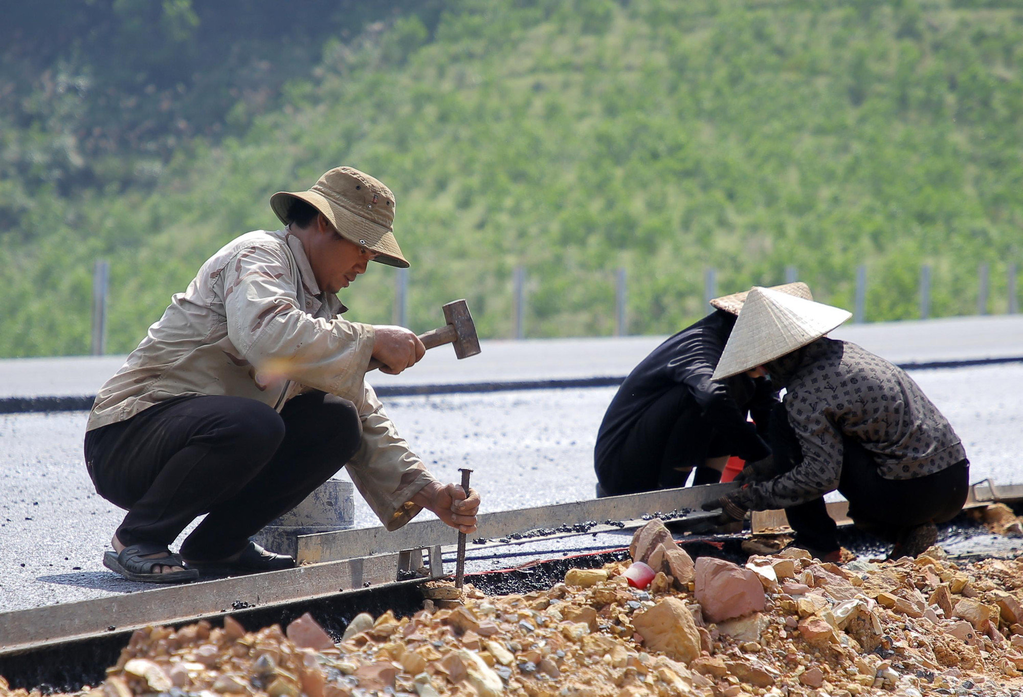 Công nhân tập trung triển khai các công đoạn để thảm bê tông nhựa.