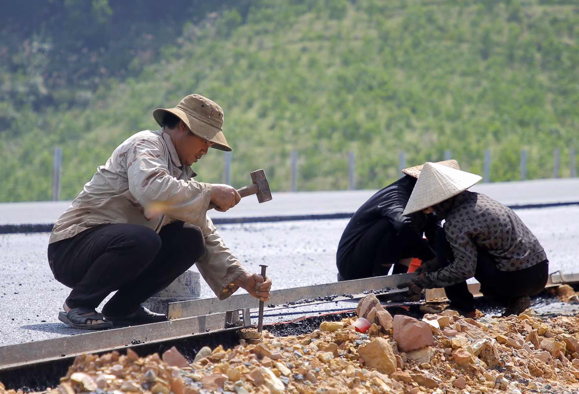 Công nhân tập trung triển khai các công đoạn để thảm bê tông nhựa.