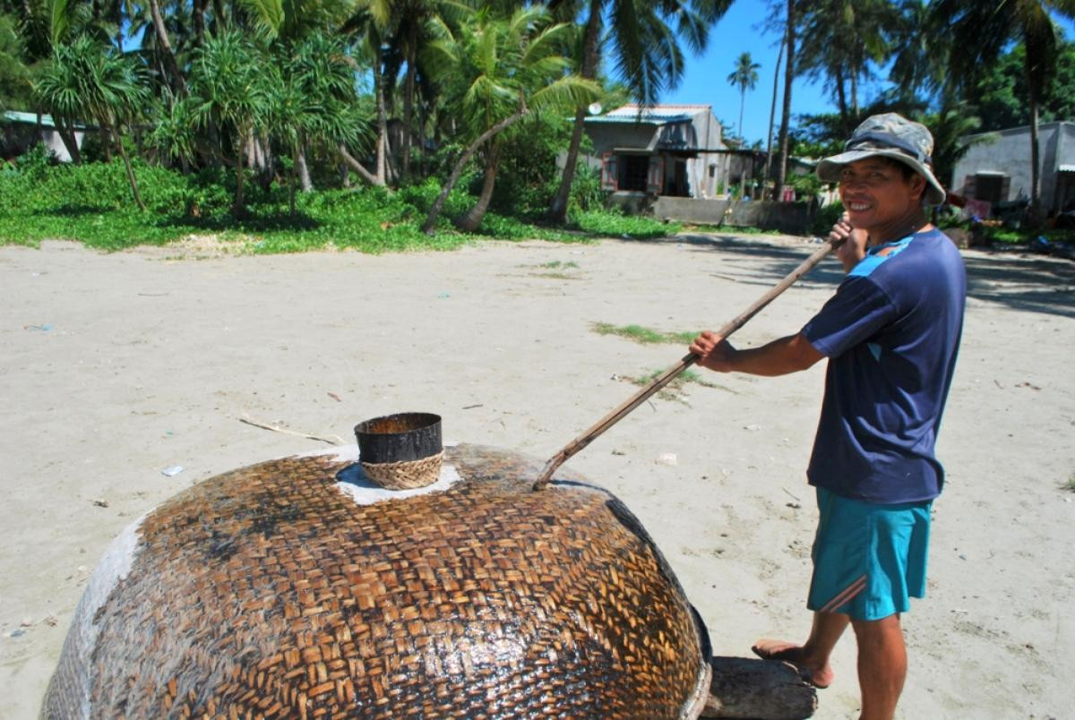 Ngư dân sửa thúng trên bãi biển.