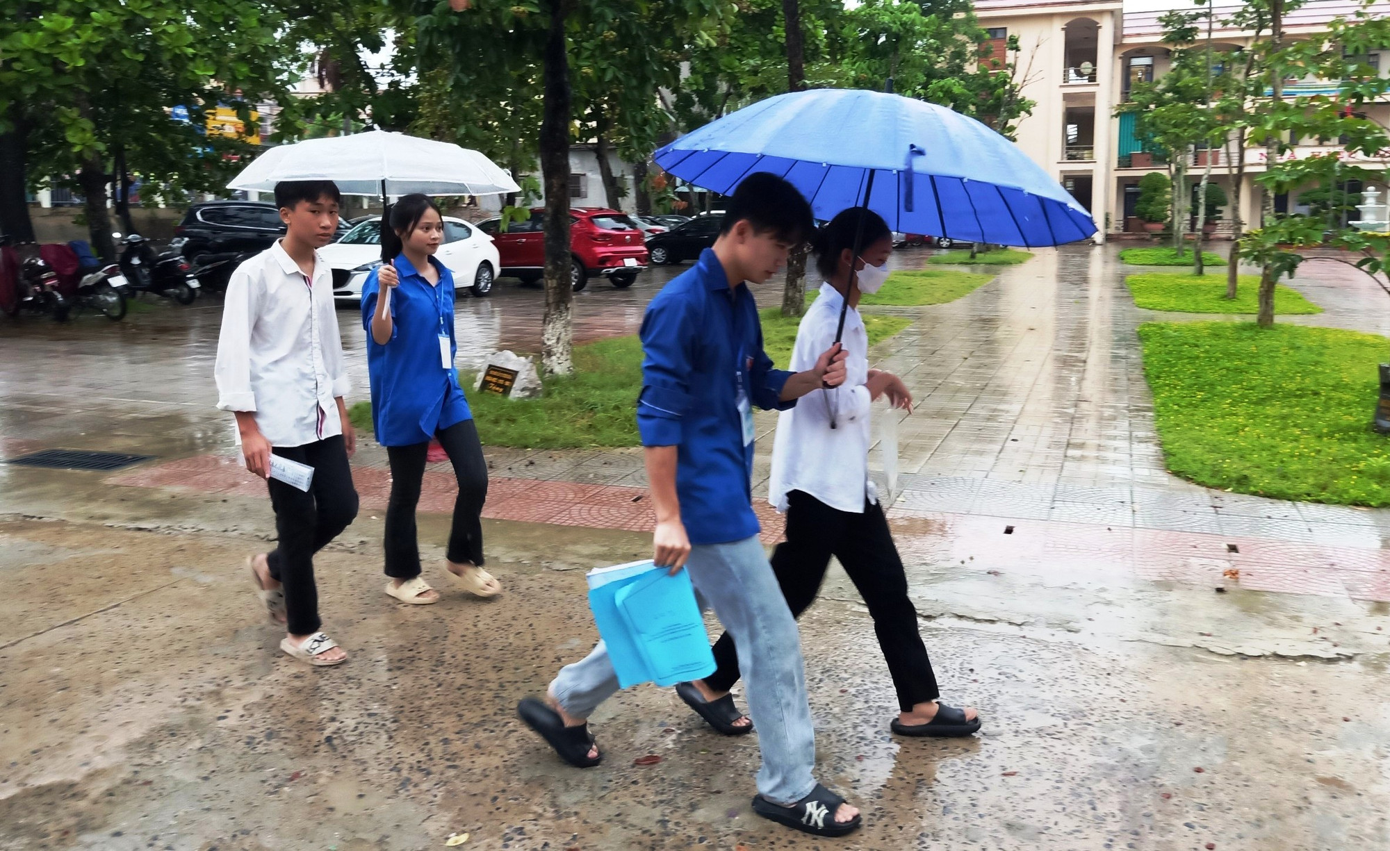 Thanh niên tình nguyện che mưa cho thí sinh vào phòng thi. Ảnh: TL. Thanh niên tình nguyện che mưa cho thí sinh vào phòng thi. Ảnh: TL.