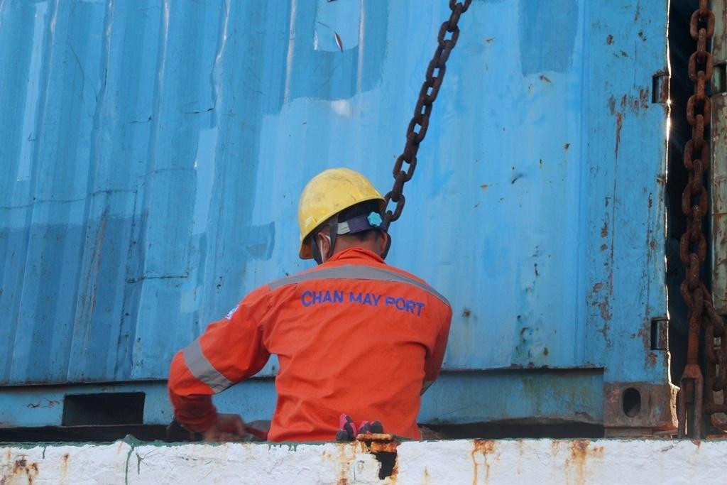 Nhân viên kỹ thuật Cảng Chân Mây đang móc dây xích vào thùng hàng container đầu tiên.