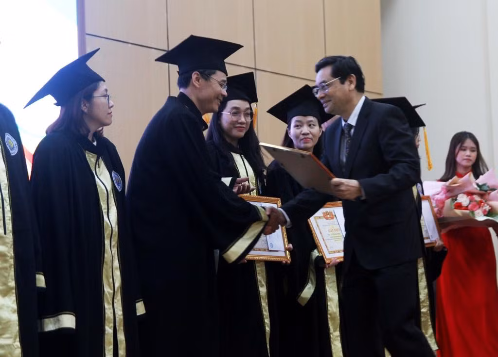 Hiệu trưởng nhà trường tặng Bằng khen cho các tân thạc sĩ có thành tích tốt.