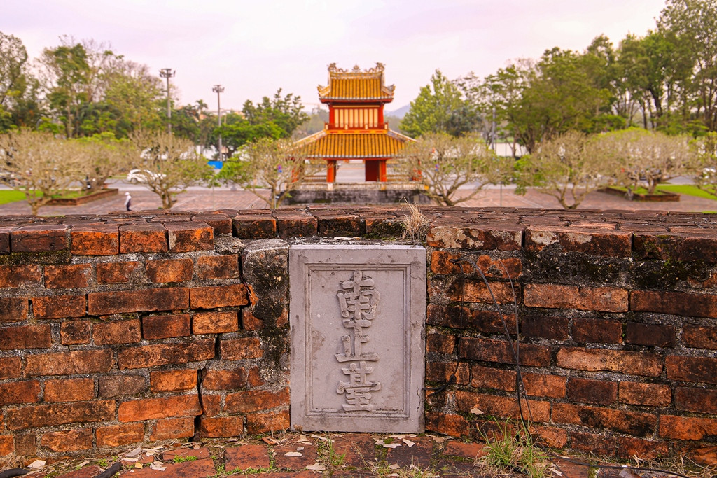 Bia khắc chữ trên bờ thành, đối diện bên kia bờ là Phu Văn Lâu.