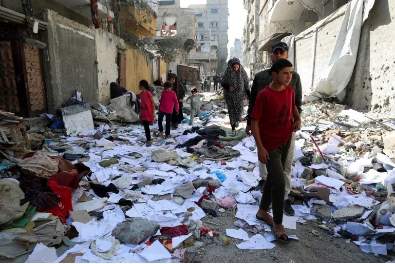 Người dân Palestine đi bộ tại địa điểm Israel không kích một ngôi nhà ở phía bắc Gaza ngày 18/4. Ảnh: Mahmoud Issa/Reuters.