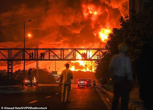 Người dân Iran nhìn khói và lửa bốc lên từ một nhà máy lọc dầu ở Tehran sau khi nơi này bị trúng đòn không kích của Israel vào đêm qua sipri-neu-dich-danh-ke-co-the-cham-ngoi-the-chien-iii-va-tham-hoa-hat-nhan-2.jpg