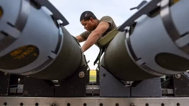 Một phi công của Phi đội máy bay ném bom thế hệ 393 đang chuẩn bị bom tấn công trực tiếp GBU-38 để lắp vào máy bay ném bom tàng hình B-2 Spirit.