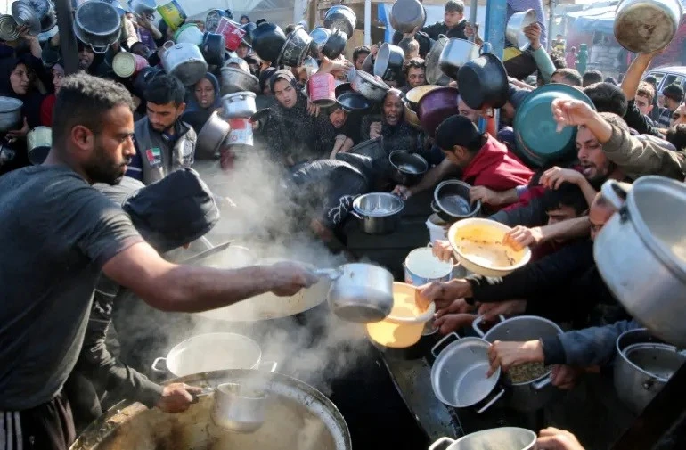 Người dân Palestine tụ tập để nhận thực phẩm do một bếp ăn từ thiện nấu tại Khan Younis vào ngày 2/1. Ảnh: Hatem Khaled/Reuters