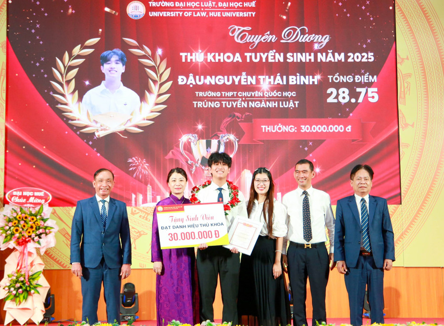 Đậu Nguyễn Thái Bình nhận học bổng, chụp ảnh lưu với lãnh đạo Trường Đại học Luật, Đại học Huế và gia đình tại Lễ khai giảng năm học mới. (Ảnh: Hoàng Hải)