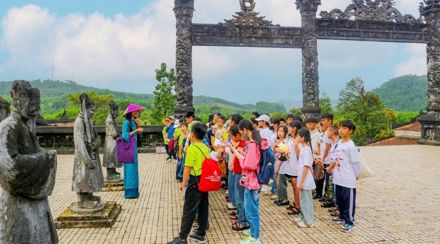 Học sinh tham quan, nghe thuyết minh các câu chuyện về văn hóa, lịch sử tại di tích Huế để vun đắp tình yêu với di sản truyền thống.