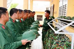 Cán bộ Trung đội 11 (Đại đội 4, Tiểu đoàn 1, Trung đoàn 48, Sư đoàn 3-Sao Vàng, Quân khu 1) hướng dẫn chiến sĩ mới cách đặt mũ. Ảnh: Lê Quang Hội 