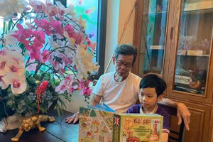 Cụ Nguyễn Hồng Dũng đọc sách cùng Minh Quang. Ảnh: NVCC