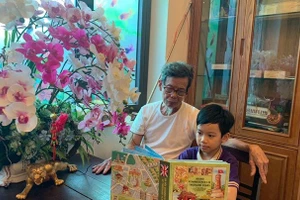 Cụ Nguyễn Hồng Dũng đọc sách cùng Minh Quang. Ảnh: NVCC