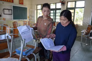 Giáo viên Trường Tiểu học Phạm Hồng Thái (Lam Thành, Nghệ An) kiểm tra lại đồ dùng, sách vở học sinh sau lũ. Ảnh Hồ Lài