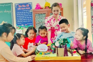 Học sinh Trường Tiểu học Nguyễn Đình Chiểu thích thú với mô hình chợ quê được làm từ rác thải bỏ đi. Ảnh: Quách Mến