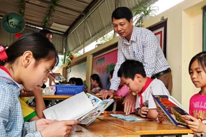 Thầy Đặng Xuân Viên - Hiệu trưởng Trường Tiểu học Thanh Xuân, xã Phú Xuân (huyện Quan Hóa, Thanh Hóa) và học sinh trong giờ đọc sách ở thư viện nhà trường.