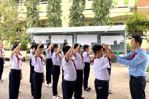 Thầy Nguyễn Chí Tài hướng dẫn học sinh tập nghi thức đội. Ảnh: Quách Mến